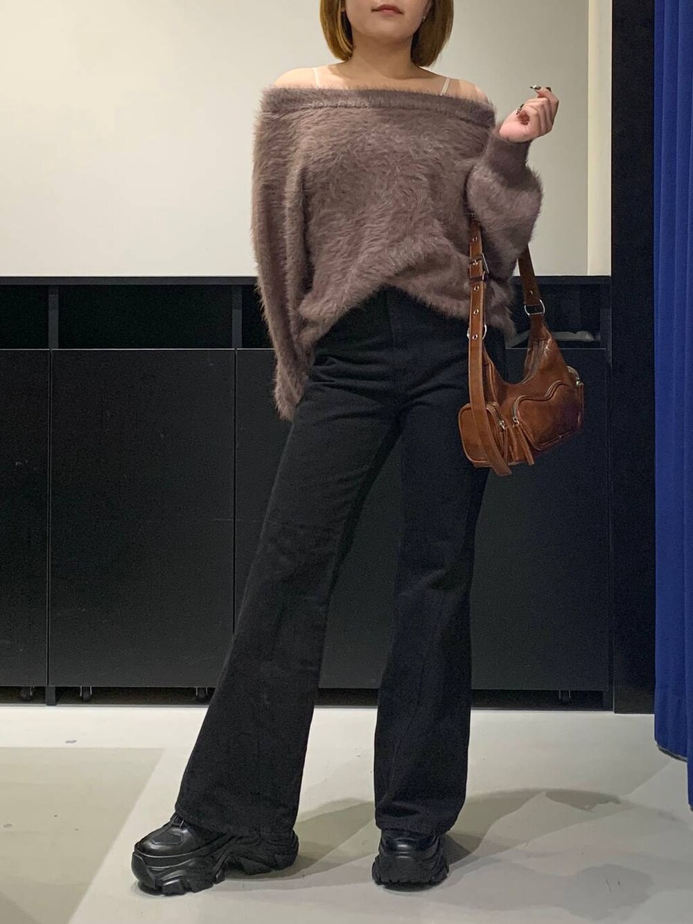 ブラック系のスニーカー、ブラック系のデニムパンツ、ブラウン系のニット/セーターを着用したレディースの冬コーディネートの2枚目の写真