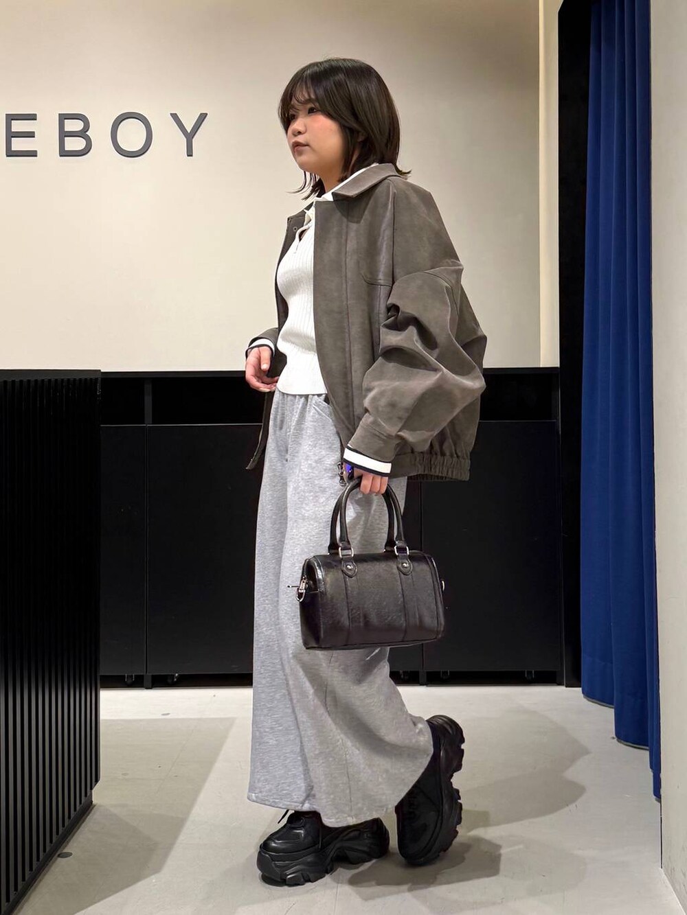 ブラック系のスニーカー、ブラック系のボストンバッグ、ホワイト系のニット/セーターを着用したレディースの冬コーディネートの7枚目の写真