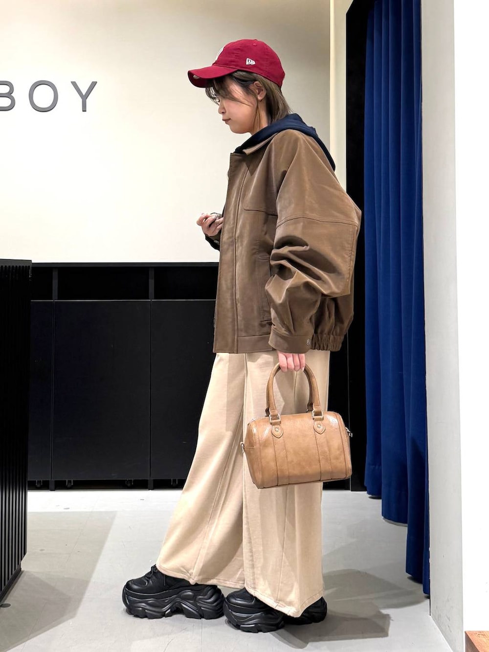 ブラック系のスニーカー、ブラウン系のボストンバッグ、ブルー系のパーカーを着用したレディースの冬コーディネートの6枚目の写真