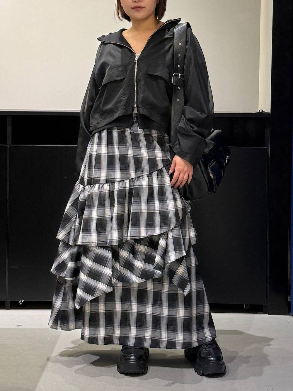 ブラック系のスニーカー、ブラック系のショルダーバッグ、ホワイト系のスカートを着用したレディースの秋コーディネートの2枚目の写真