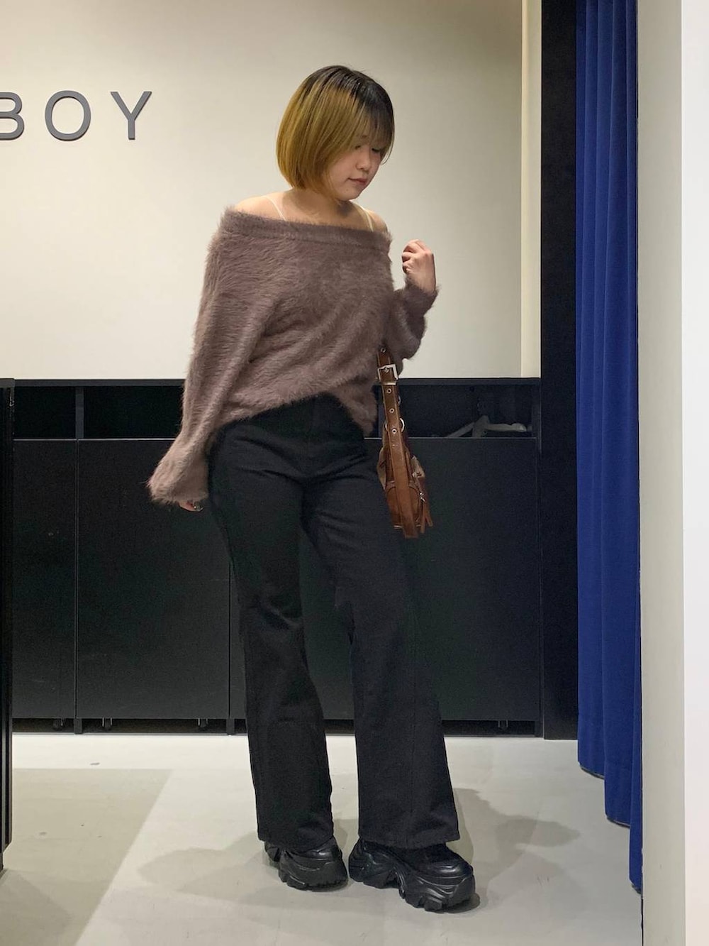 ブラック系のスニーカー、ブラック系のデニムパンツ、ブラウン系のニット/セーターを着用したレディースの冬コーディネートの3枚目の写真