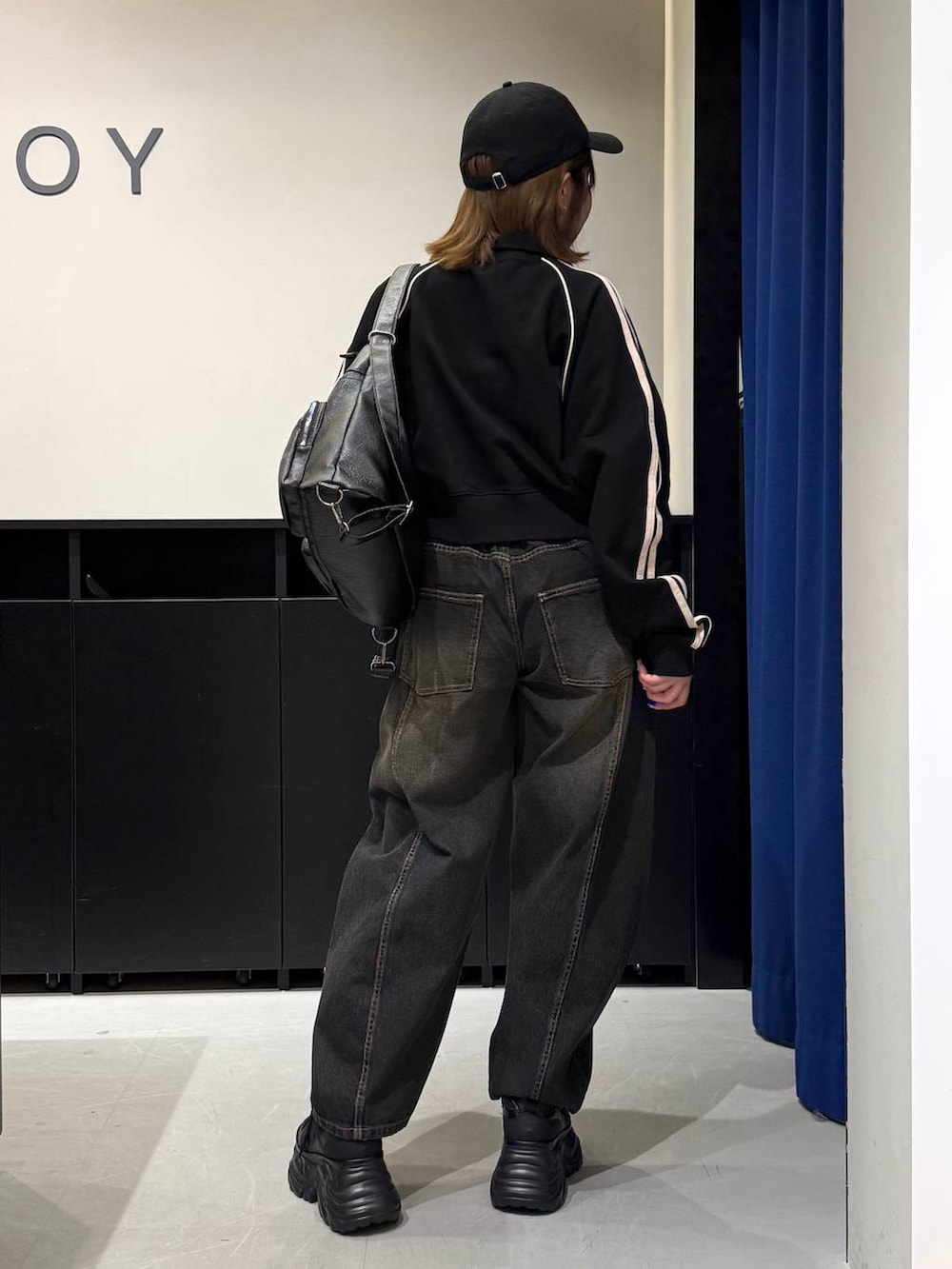 ブラック系のスニーカー、ブラック系のデニムパンツ、ブラック系のショルダーバッグを着用したレディースの冬コーディネートの5枚目の写真