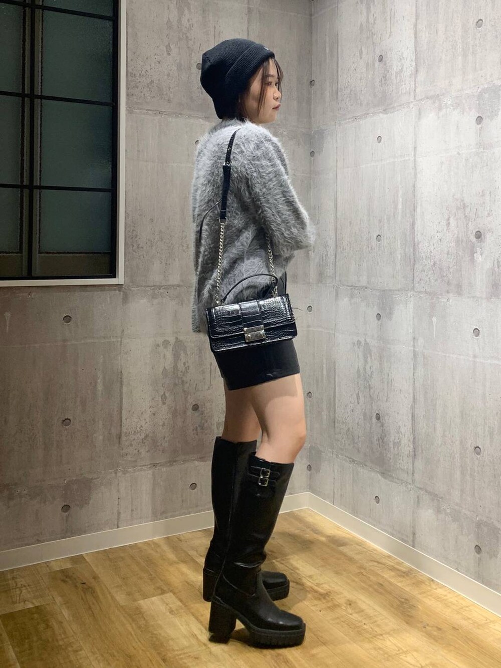 ブラック系のブーツ、ブラック系のハンドバッグ、グレー系のニット/セーターを着用したレディースの秋コーディネートの4枚目の写真