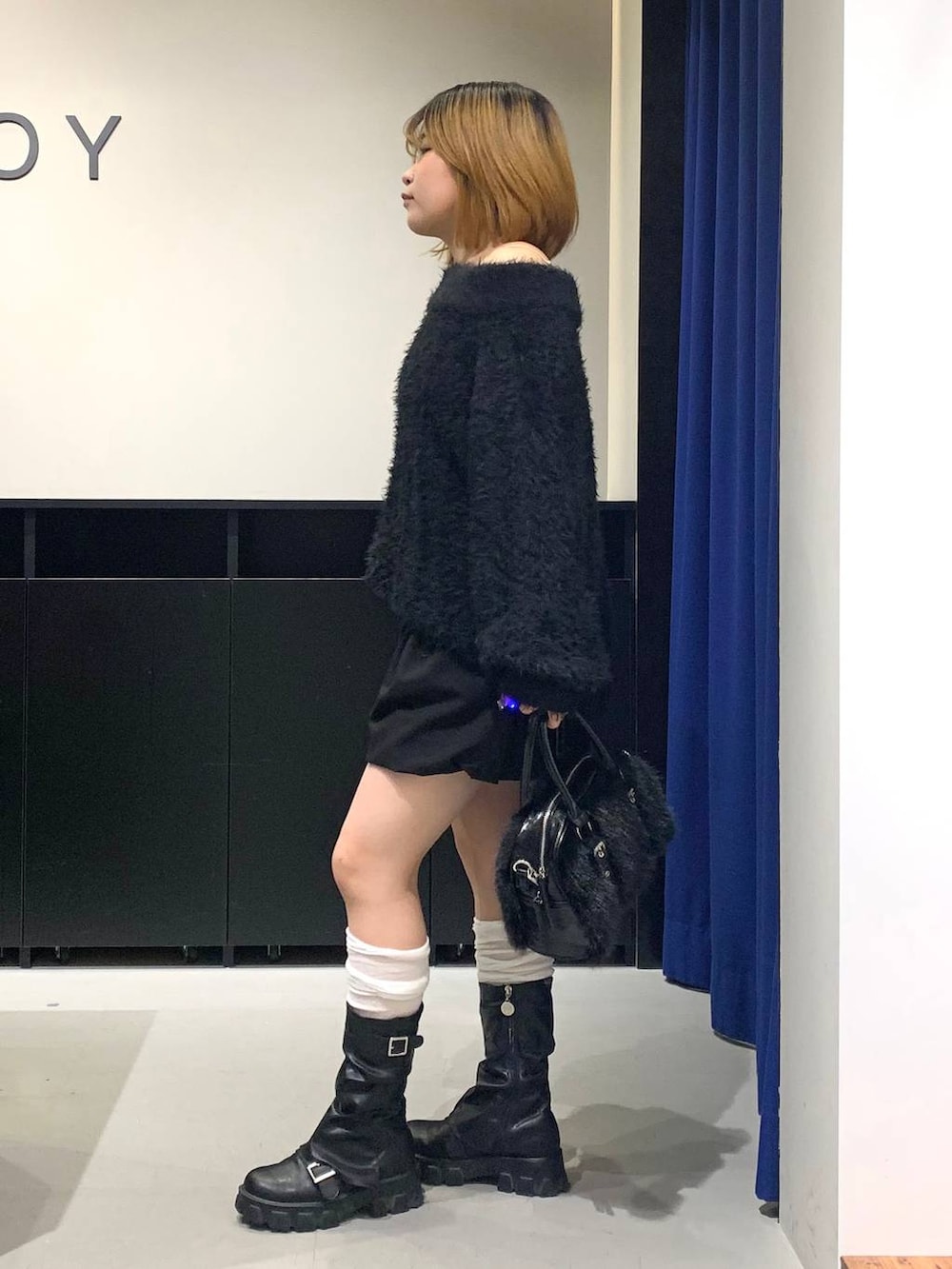 ホワイト系のキャミソール、ブラック系のワンピース、ブラック系のボストンバッグを着用したレディースの冬コーディネートの6枚目の写真