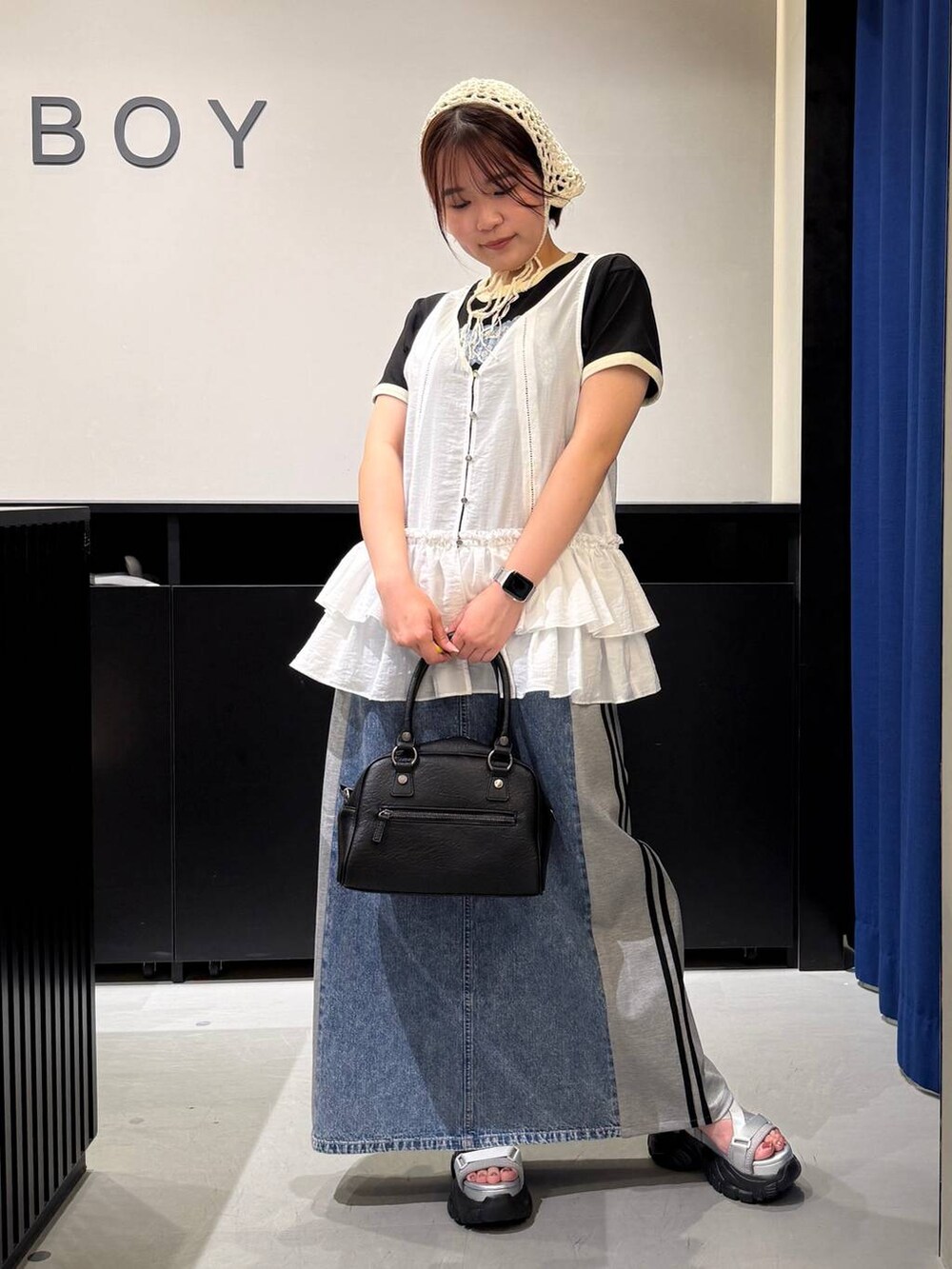 グレー系のサンダル、ブルー系のスカート、ブラック系のショルダーバッグを着用したレディースの夏コーディネートの3枚目の写真