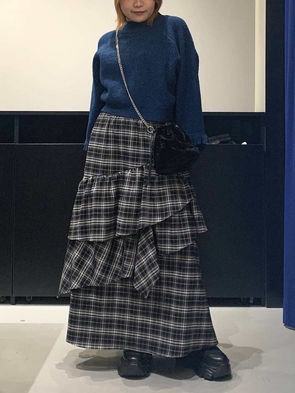 ブラック系のブーツ、ブラック系のスカート、ブラック系のハンドバッグを着用したレディースの冬コーディネートの2枚目の写真