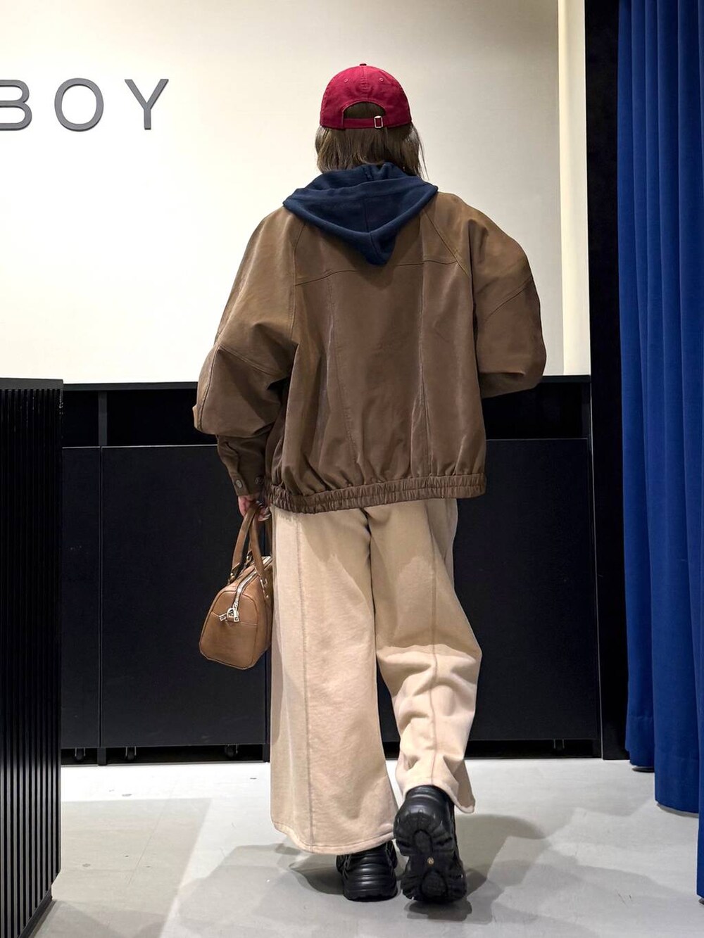 ブラック系のスニーカー、ブラウン系のボストンバッグ、ブルー系のパーカーを着用したレディースの冬コーディネートの5枚目の写真