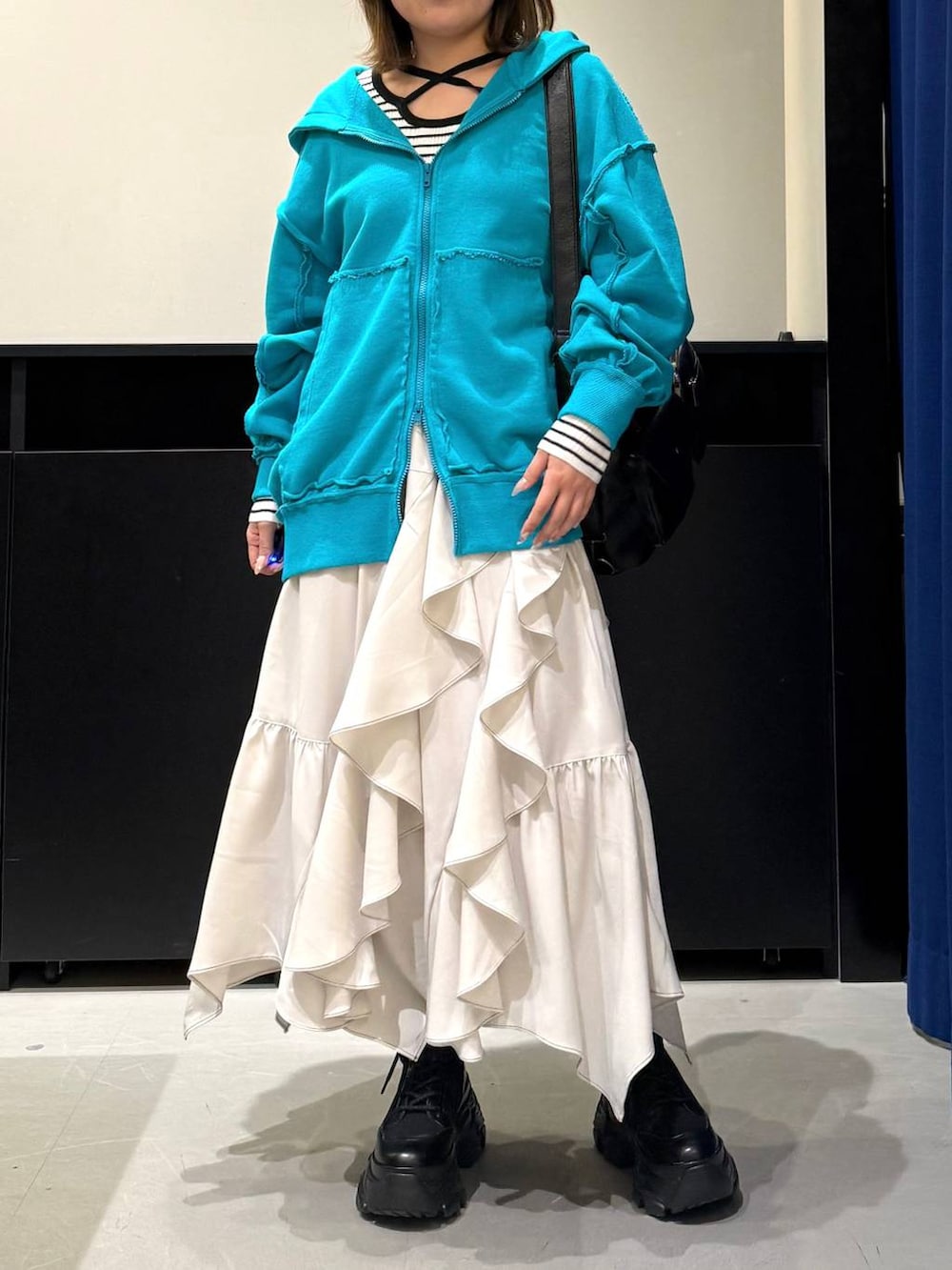 ブラック系のブーツ、ベージュ系のスカート、ホワイト系のニット/セーターを着用したレディースの冬コーディネートの2枚目の写真