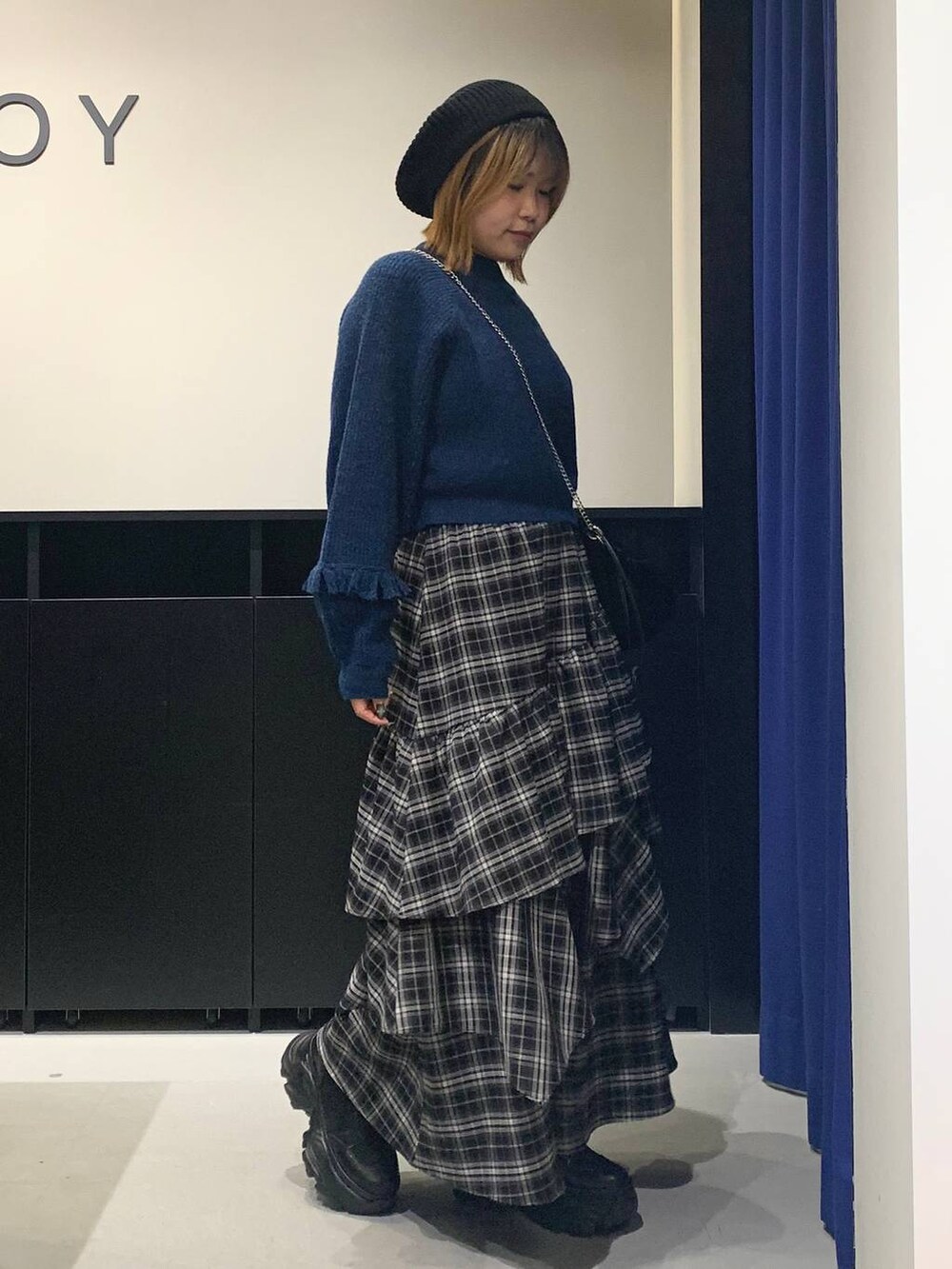 ブラック系のブーツ、ブラック系のスカート、ブラック系のハンドバッグを着用したレディースの冬コーディネートの3枚目の写真