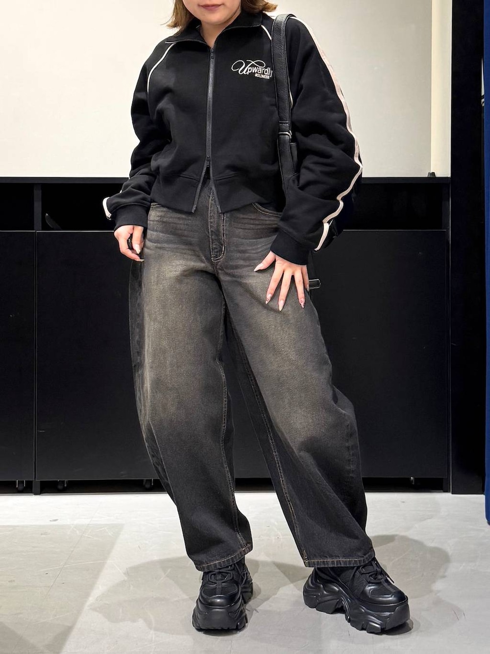 ブラック系のスニーカー、ブラック系のデニムパンツ、ブラック系のショルダーバッグを着用したレディースの冬コーディネートの2枚目の写真