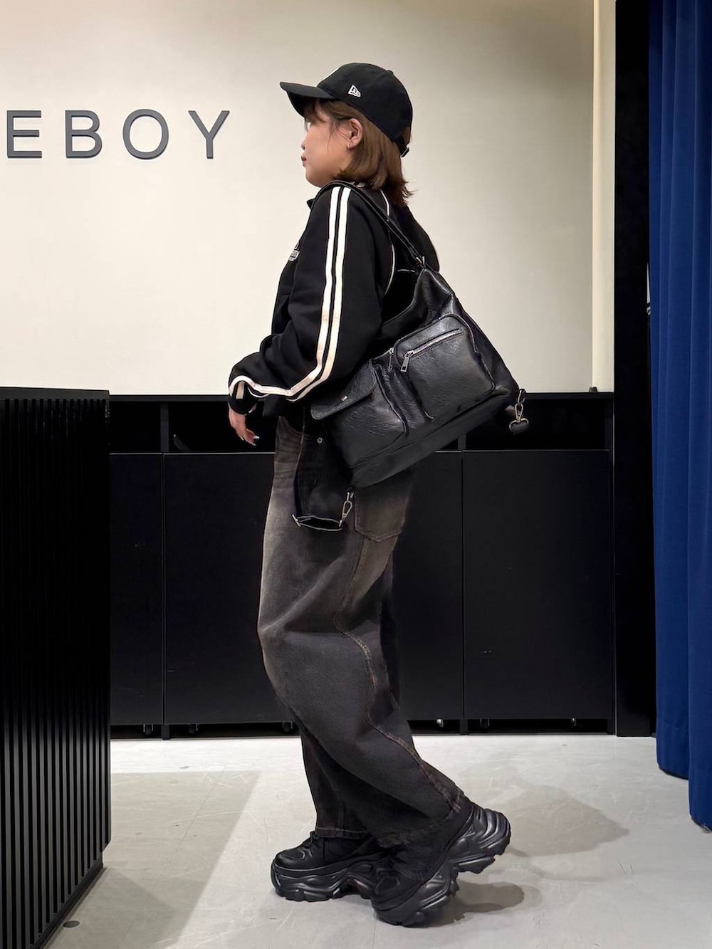 ブラック系のスニーカー、ブラック系のデニムパンツ、ブラック系のショルダーバッグを着用したレディースの冬コーディネートの6枚目の写真