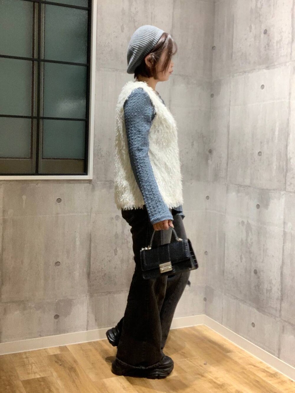 ブラック系のスニーカー、ブラック系のデニムパンツ、ホワイト系のベストを着用したレディースの秋コーディネートの4枚目の写真