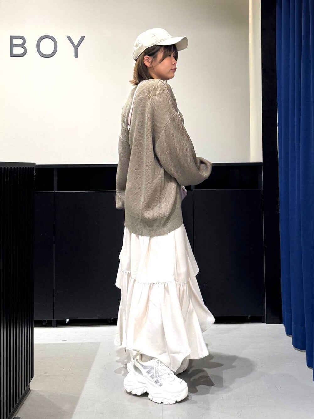 ホワイト系のスニーカー、ベージュ系のスカート、ピンク系のハンドバッグを着用したレディースの冬コーディネートの4枚目の写真