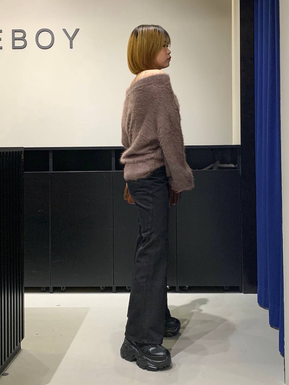 ブラック系のスニーカー、ブラック系のデニムパンツ、ブラウン系のニット/セーターを着用したレディースの冬コーディネートの4枚目の写真