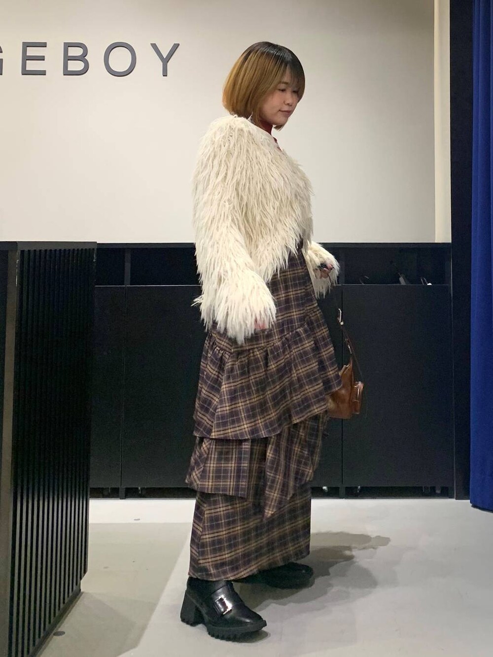 ブラック系のブーツ、ブラウン系のスカート、ブラウン系のショルダーバッグを着用したレディースの冬コーディネートの3枚目の写真