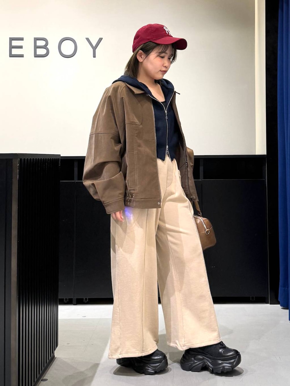 ブラック系のスニーカー、ブラウン系のボストンバッグ、ブルー系のパーカーを着用したレディースの冬コーディネートの3枚目の写真