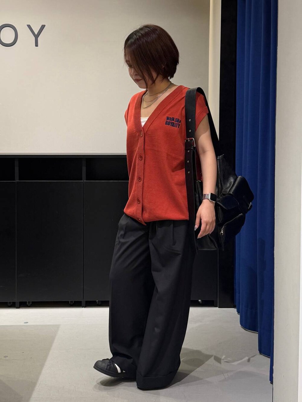 ホワイト系のキャミソール、ブラック系のスラックス、オレンジ系のベストを着用したレディースの夏コーディネートの7枚目の写真