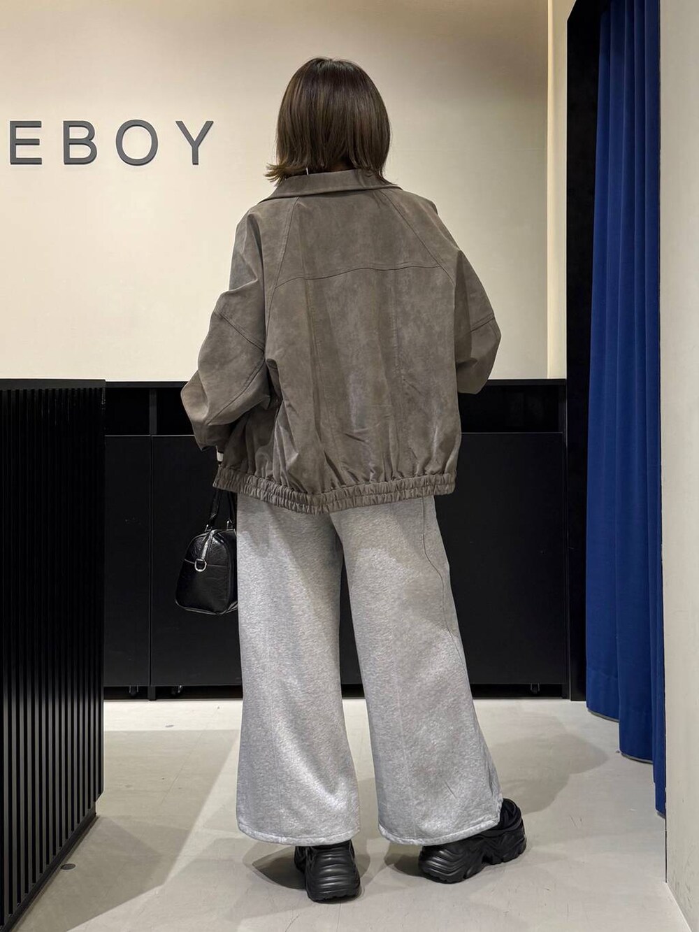 ブラック系のスニーカー、ブラック系のボストンバッグ、ホワイト系のニット/セーターを着用したレディースの冬コーディネートの5枚目の写真