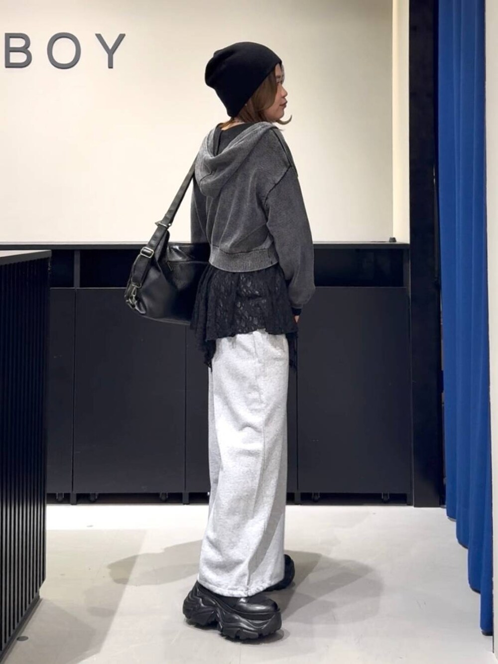 ブラック系のブーツ、グレー系のパーカー、ブラック系のチュニックを着用したレディースの冬コーディネートの4枚目の写真