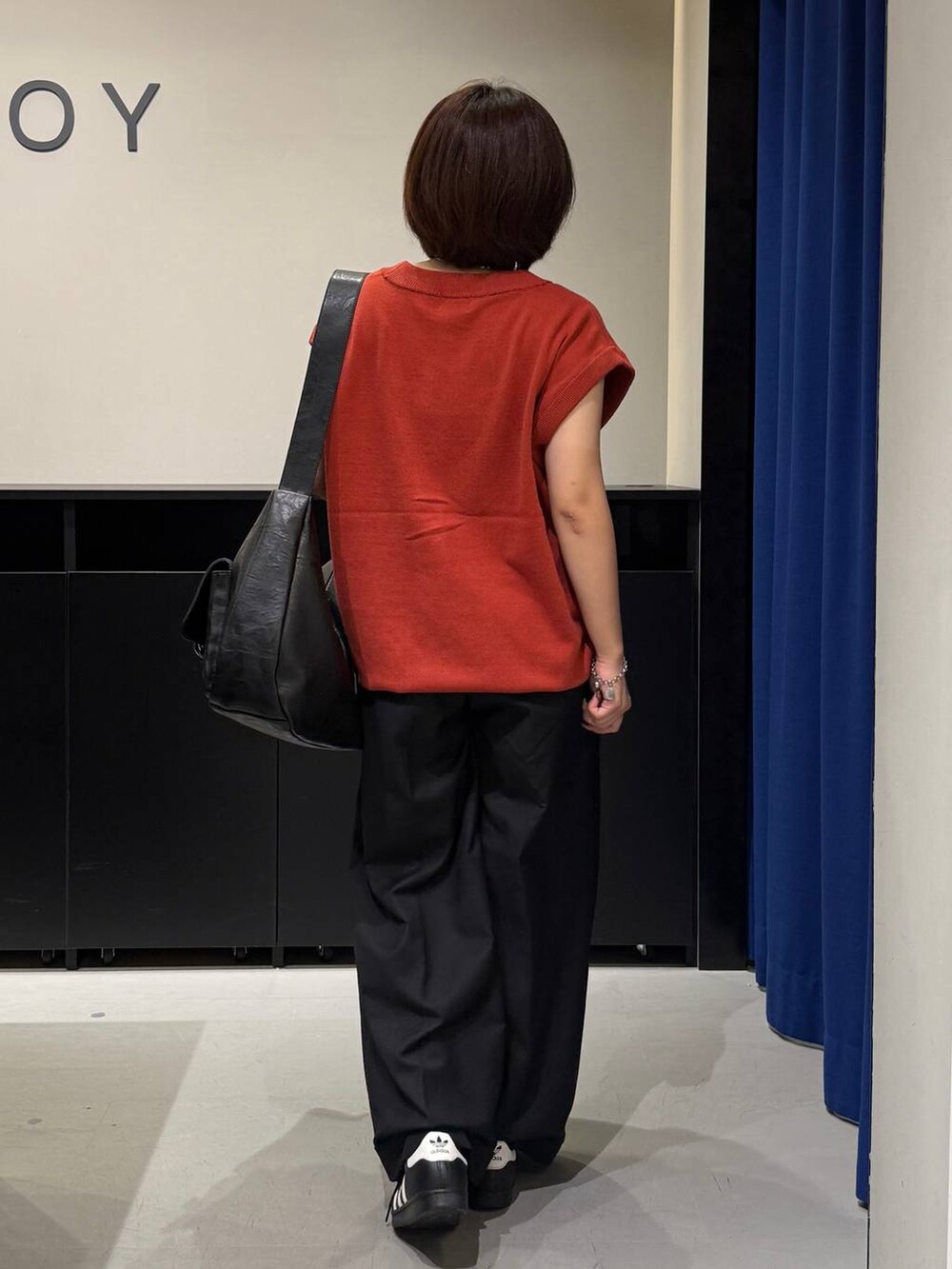 ホワイト系のキャミソール、ブラック系のスラックス、オレンジ系のベストを着用したレディースの夏コーディネートの5枚目の写真