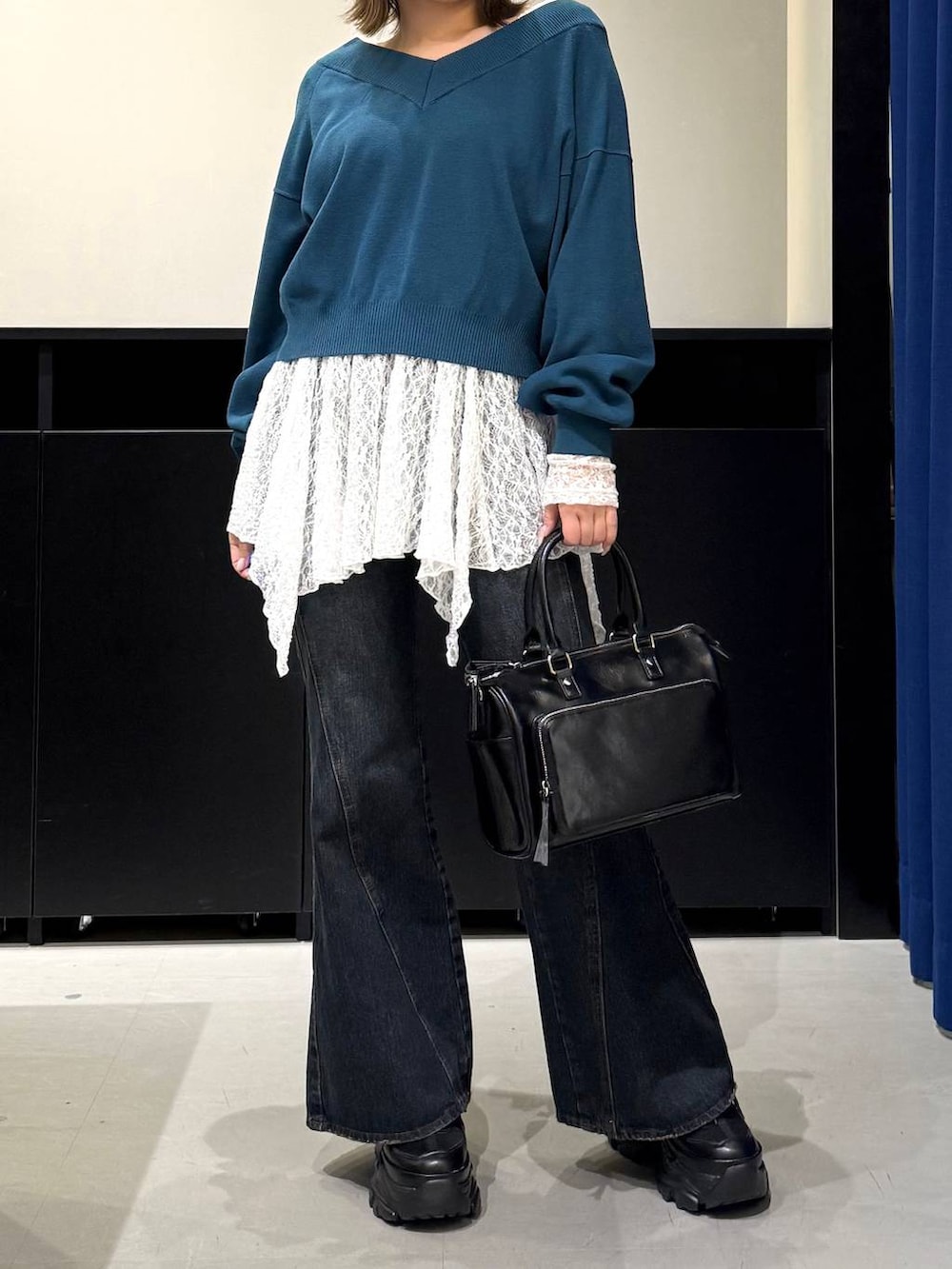 ブラック系のスニーカー、ブルー系のデニムパンツ、グリーン系のニット/セーターを着用したレディースの冬コーディネートの2枚目の写真