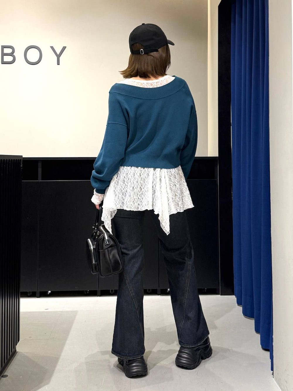 ブラック系のスニーカー、ブルー系のデニムパンツ、グリーン系のニット/セーターを着用したレディースの冬コーディネートの5枚目の写真