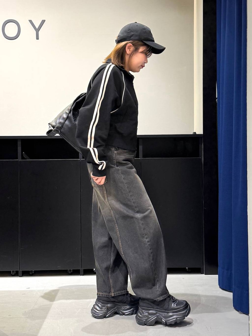 ブラック系のスニーカー、ブラック系のデニムパンツ、ブラック系のショルダーバッグを着用したレディースの冬コーディネートの4枚目の写真