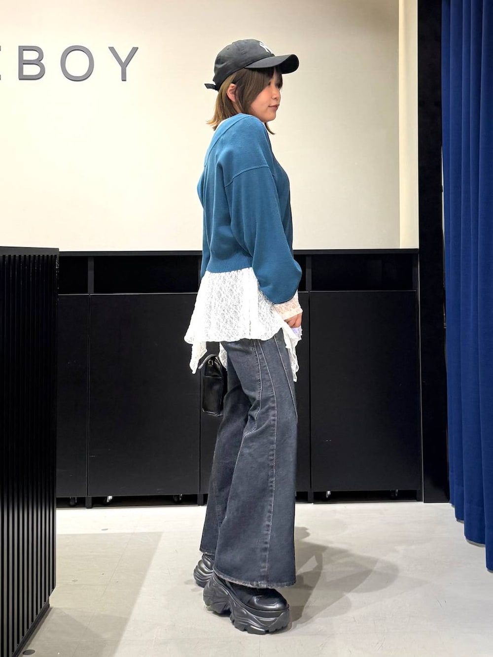 ブラック系のスニーカー、ブルー系のデニムパンツ、グリーン系のニット/セーターを着用したレディースの冬コーディネートの4枚目の写真