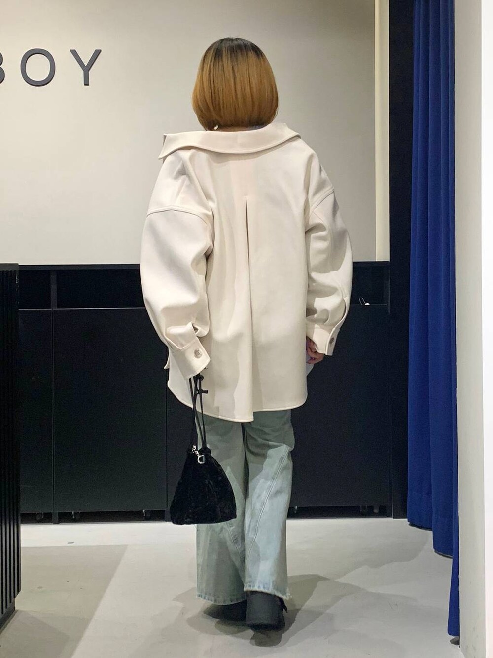 ブルー系のデニムパンツ、ホワイト系のテーラードジャケット、ブラック系のブーツを着用したレディースの冬コーディネートの5枚目の写真