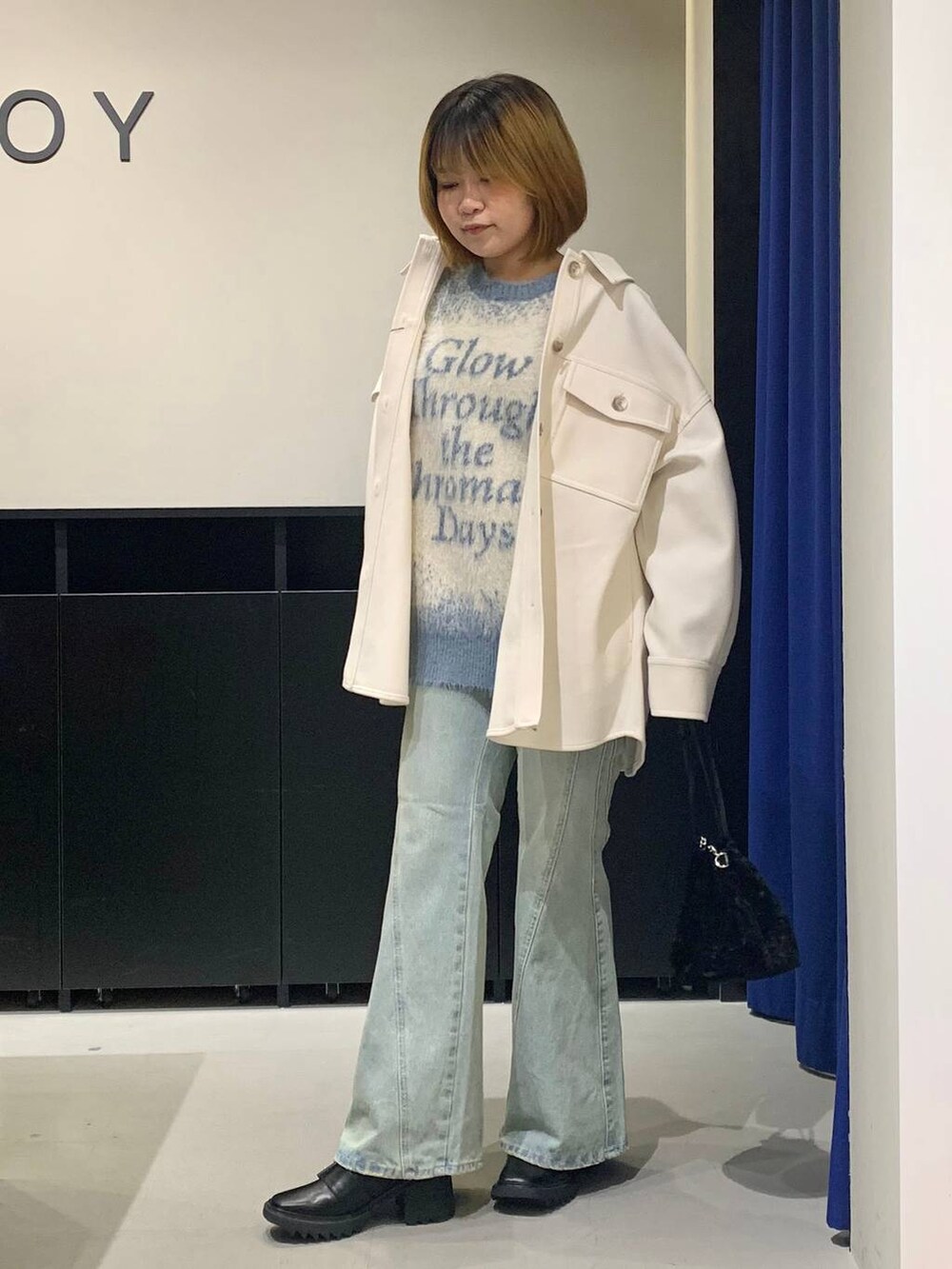 ブルー系のデニムパンツ、ホワイト系のテーラードジャケット、ブラック系のブーツを着用したレディースの冬コーディネートの7枚目の写真