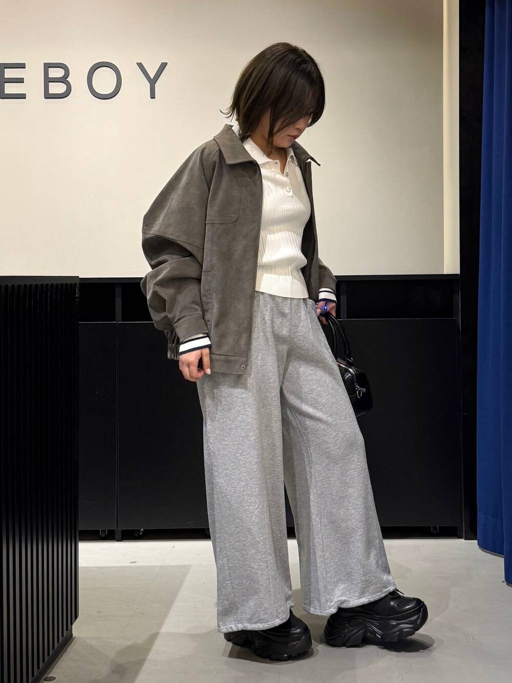 ブラック系のスニーカー、ブラック系のボストンバッグ、ホワイト系のニット/セーターを着用したレディースの冬コーディネートの3枚目の写真