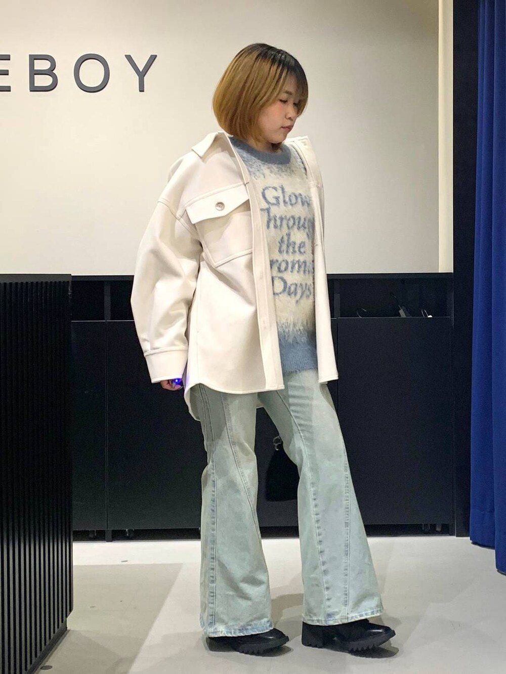 ブルー系のデニムパンツ、ホワイト系のテーラードジャケット、ブラック系のブーツを着用したレディースの冬コーディネートの3枚目の写真