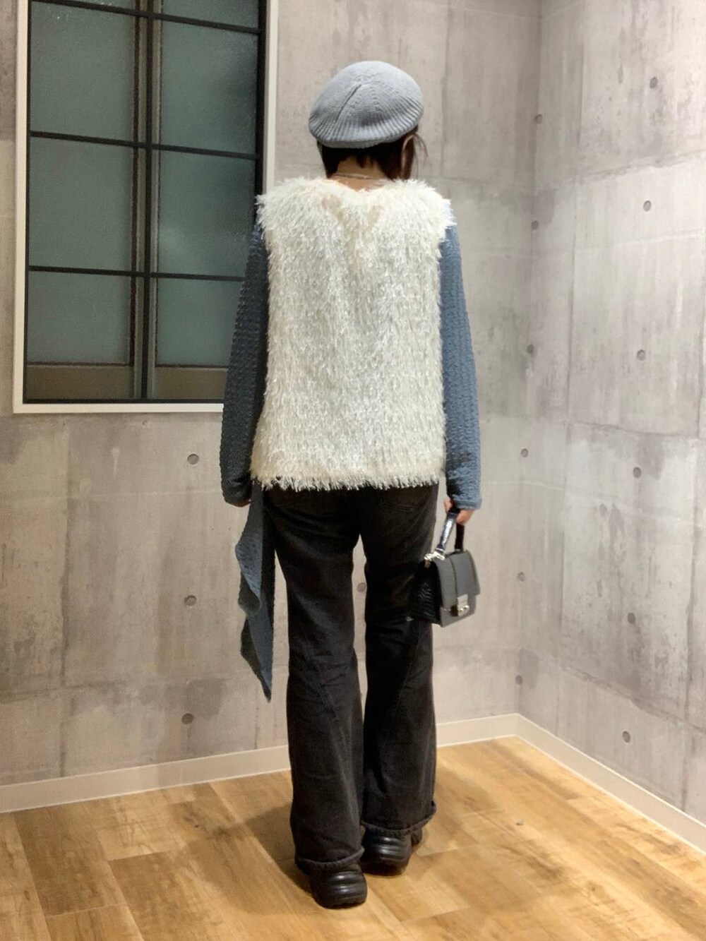 ブラック系のスニーカー、ブラック系のデニムパンツ、ホワイト系のベストを着用したレディースの秋コーディネートの5枚目の写真