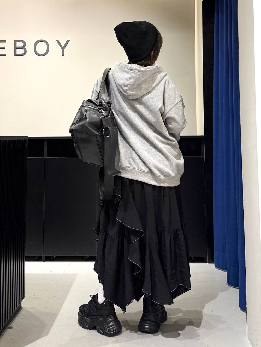 ブラック系のスニーカー、ブラック系のボストンバッグ、ブラック系のスカートを着用したレディースの冬コーディネートの5枚目の写真