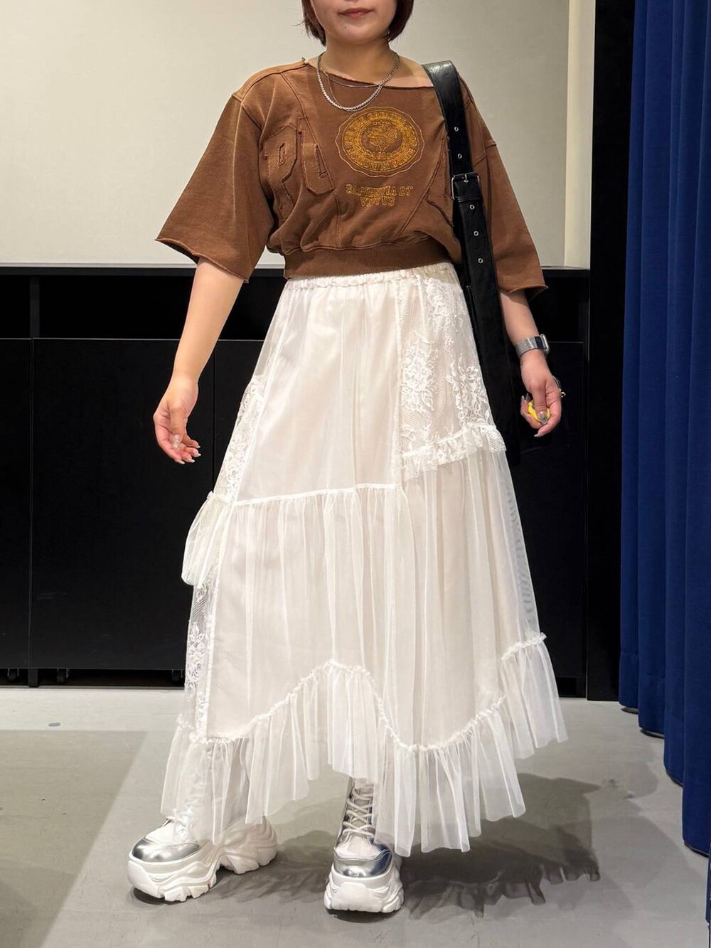 ホワイト系のブーツ、ブラウン系のTシャツ/カットソー、ブラック系のショルダーバッグを着用したレディースの夏コーディネートの2枚目の写真