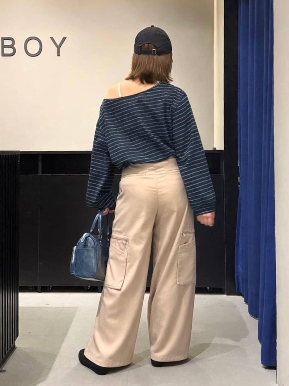 ホワイト系のキャミソール、ブルー系のショルダーバッグ、ベージュ系のスラックスを着用したレディースの冬コーディネートの4枚目の写真