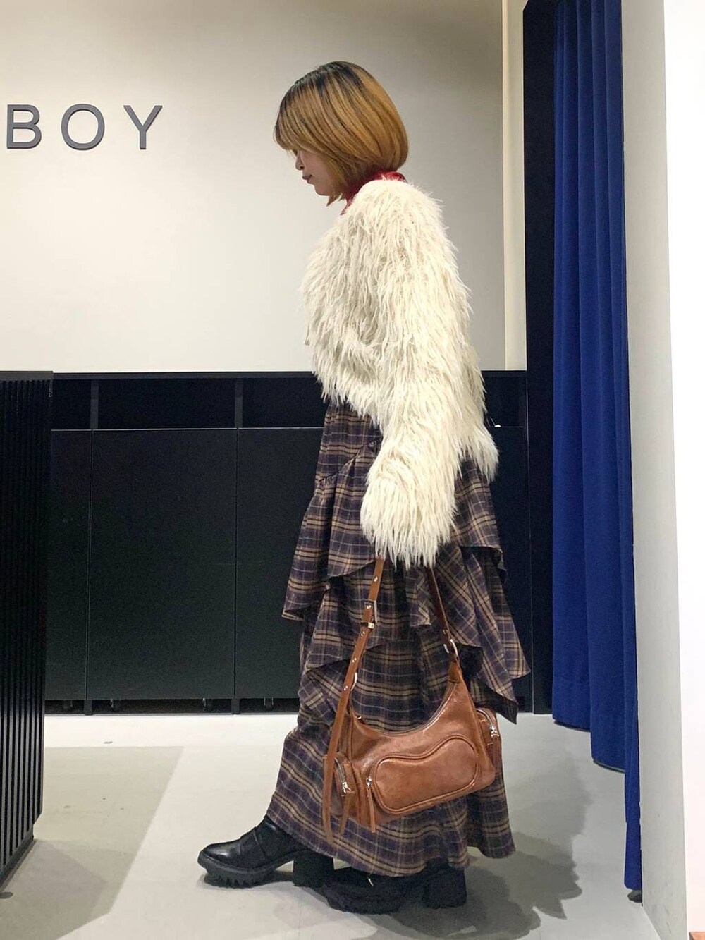 ブラック系のブーツ、ブラウン系のスカート、ブラウン系のショルダーバッグを着用したレディースの冬コーディネートの5枚目の写真