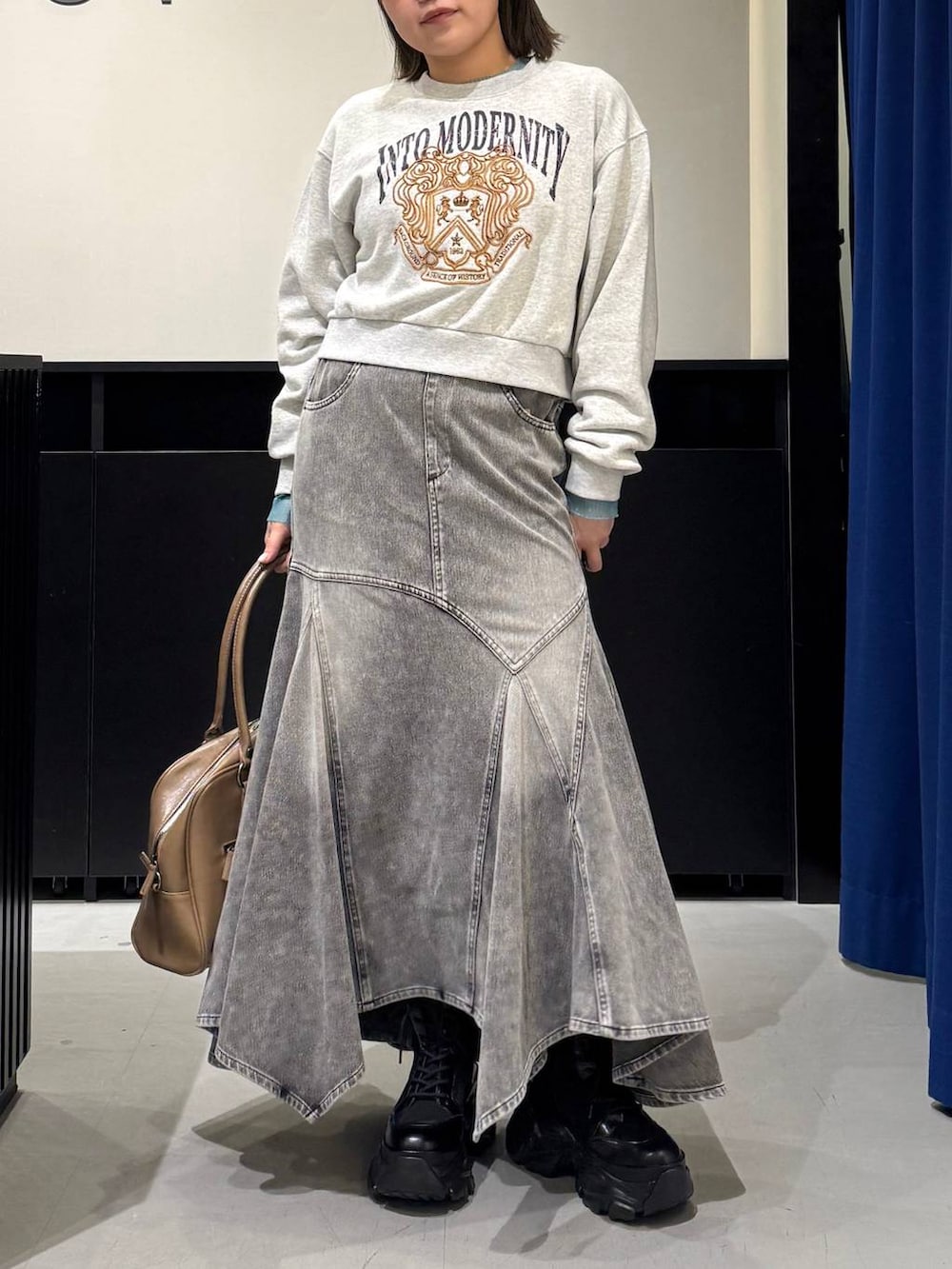 ブラック系のブーツ、イエロー系のボストンバッグ、グレー系のスウェットを着用したレディースの冬コーディネートの2枚目の写真