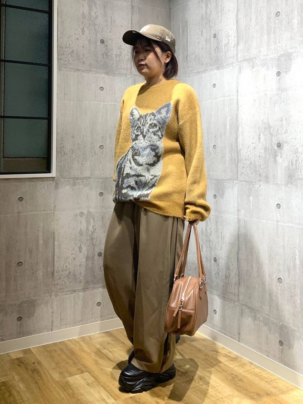 ブラック系のブーツ、イエロー系のボストンバッグ、イエロー系のニット/セーターを着用したレディースの秋コーディネートの6枚目の写真