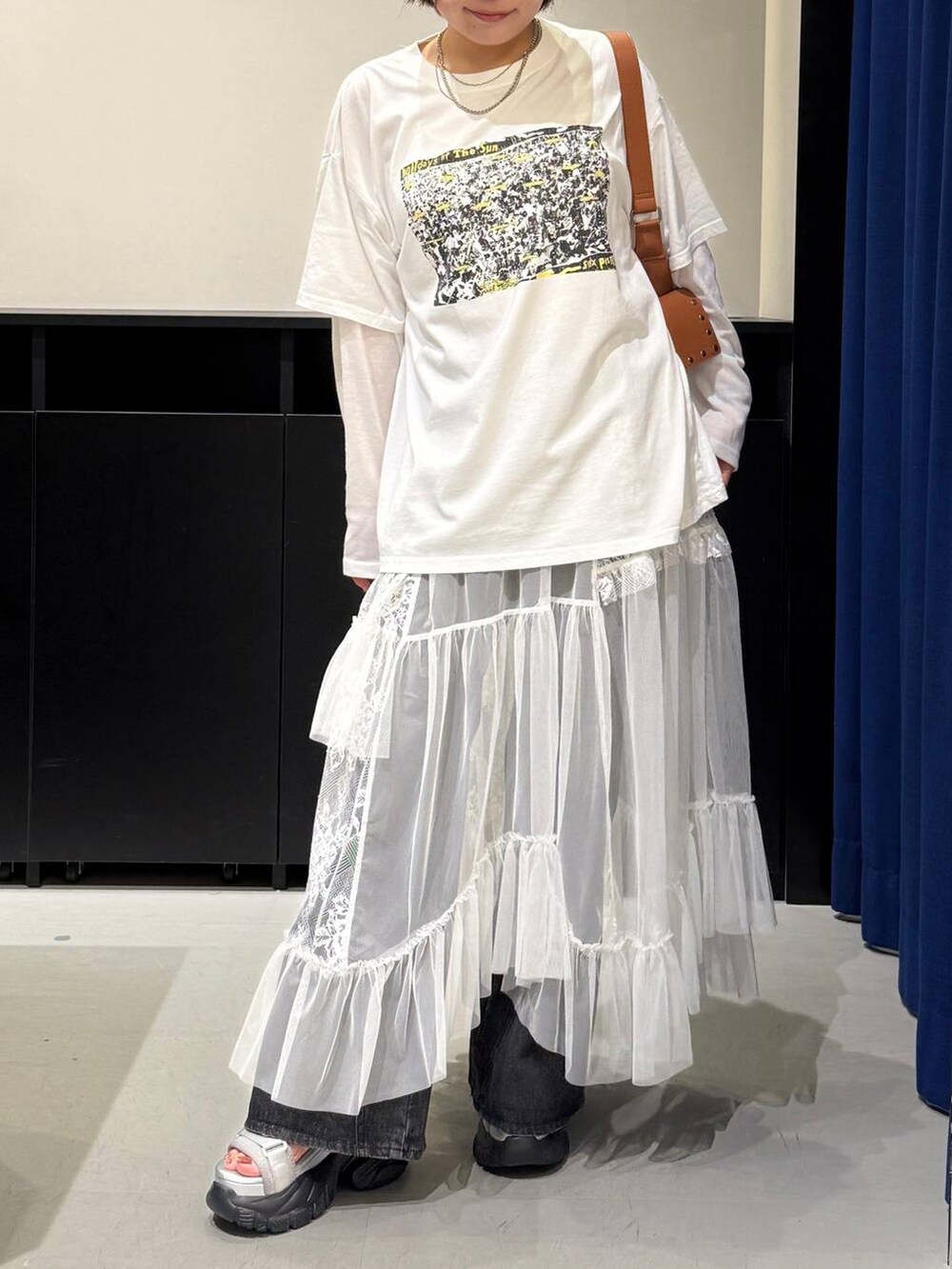 グレー系のサンダル、ブラック系のデニムパンツ、ブラウン系のショルダーバッグを着用したレディースの夏コーディネートの2枚目の写真