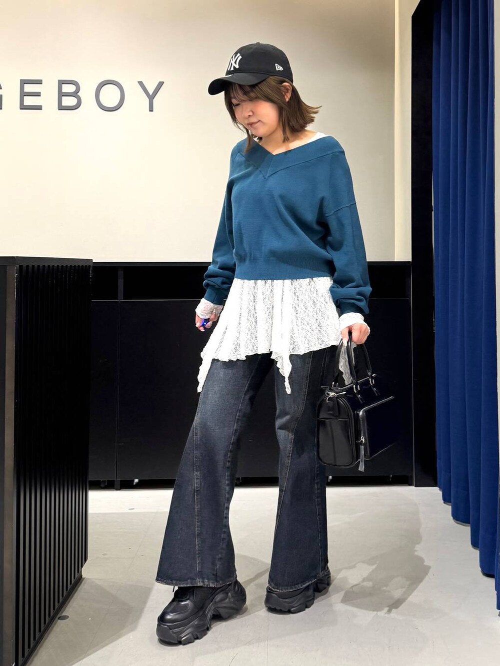 ブラック系のスニーカー、ブルー系のデニムパンツ、グリーン系のニット/セーターを着用したレディースの冬コーディネートの7枚目の写真