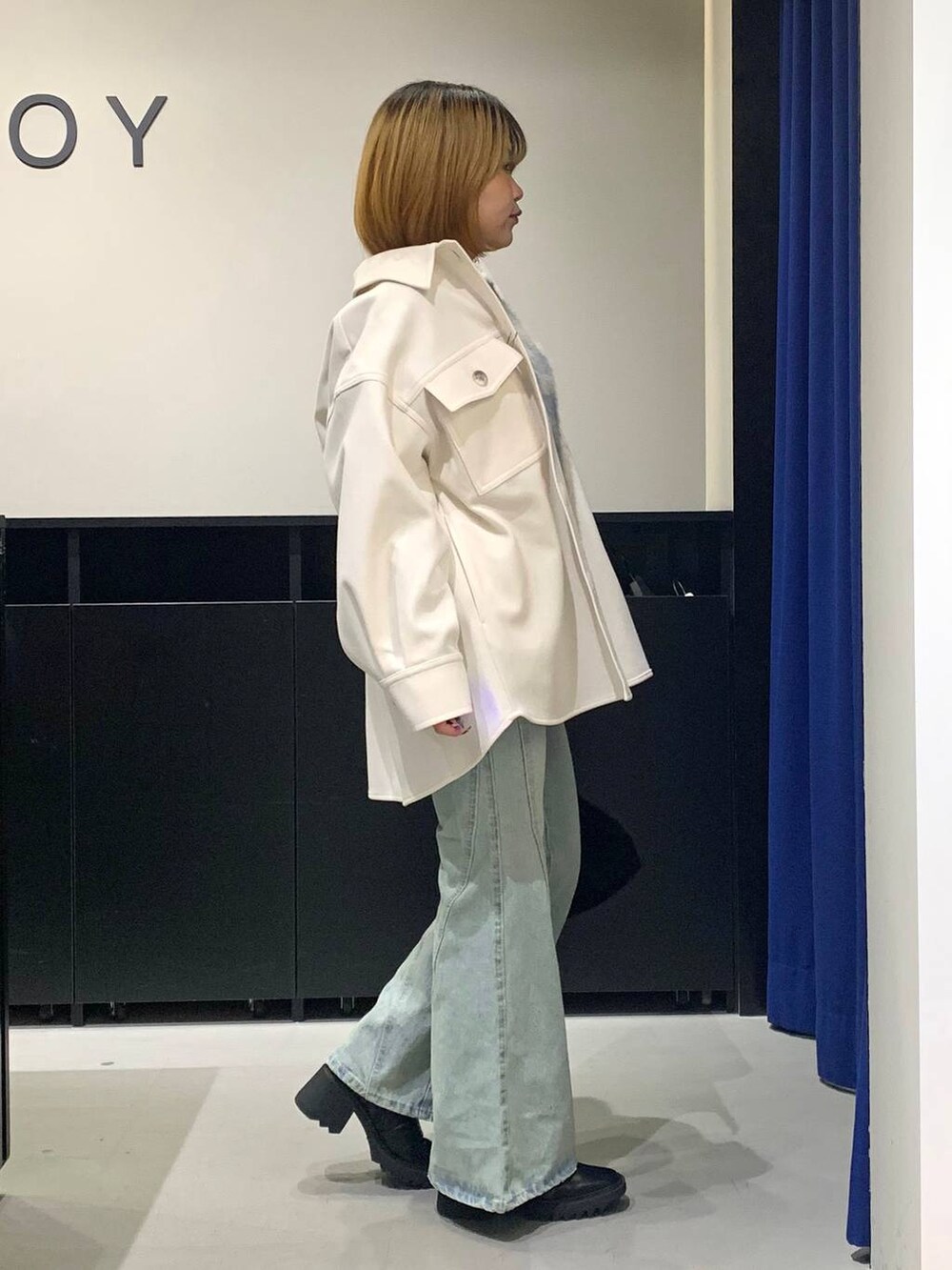 ブルー系のデニムパンツ、ホワイト系のテーラードジャケット、ブラック系のブーツを着用したレディースの冬コーディネートの4枚目の写真