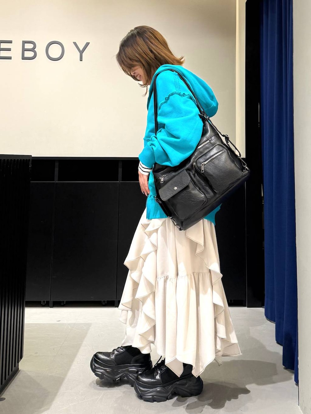 ブラック系のブーツ、ベージュ系のスカート、ホワイト系のニット/セーターを着用したレディースの冬コーディネートの5枚目の写真