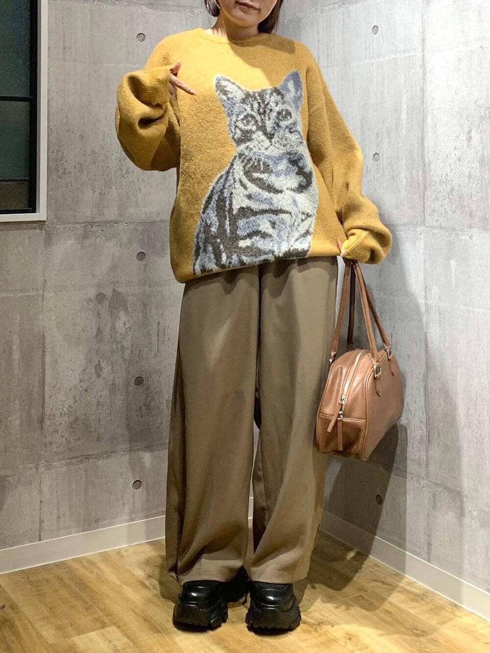 ブラック系のブーツ、イエロー系のボストンバッグ、イエロー系のニット/セーターを着用したレディースの秋コーディネートの2枚目の写真