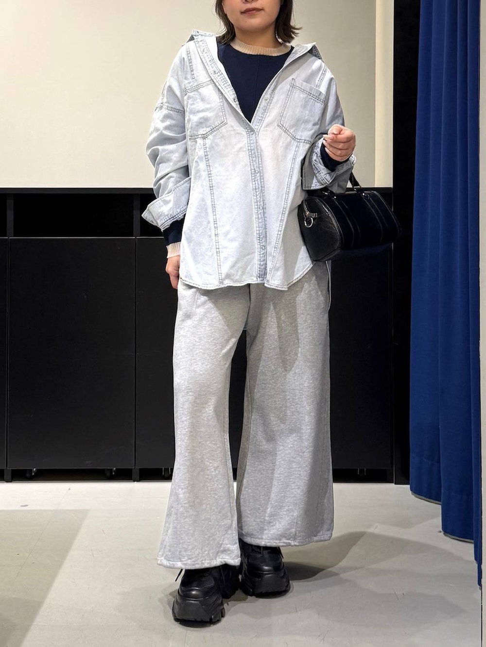 ブラック系のスニーカー、ブラック系のボストンバッグ、ブルー系のシャツ/ブラウスを着用したレディースの冬コーディネートの2枚目の写真