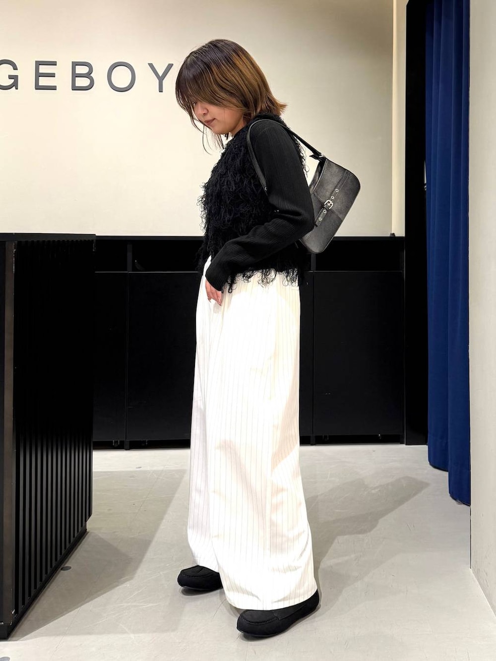 ブラック系のハンドバッグ、ブラック系のニット/セーター、ホワイト系のスラックスを着用したレディースの冬コーディネートの6枚目の写真