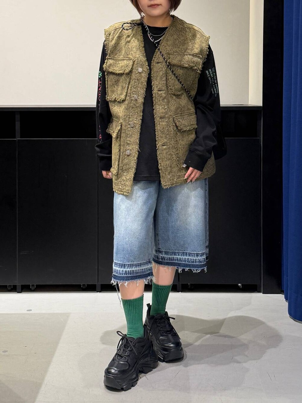 ブラック系のスニーカー、ブラック系のショルダーバッグ、ブルー系のデニムパンツを着用したレディースの夏コーディネートの2枚目の写真