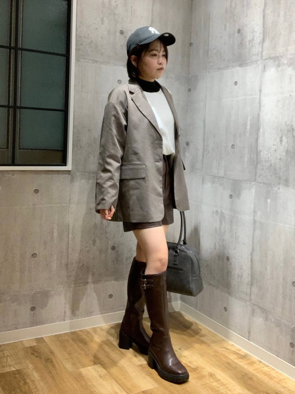 グレー系のボストンバッグ、ブラウン系のテーラードジャケット、ホワイト系のニット/セーターを着用したレディースの秋コーディネートの4枚目の写真