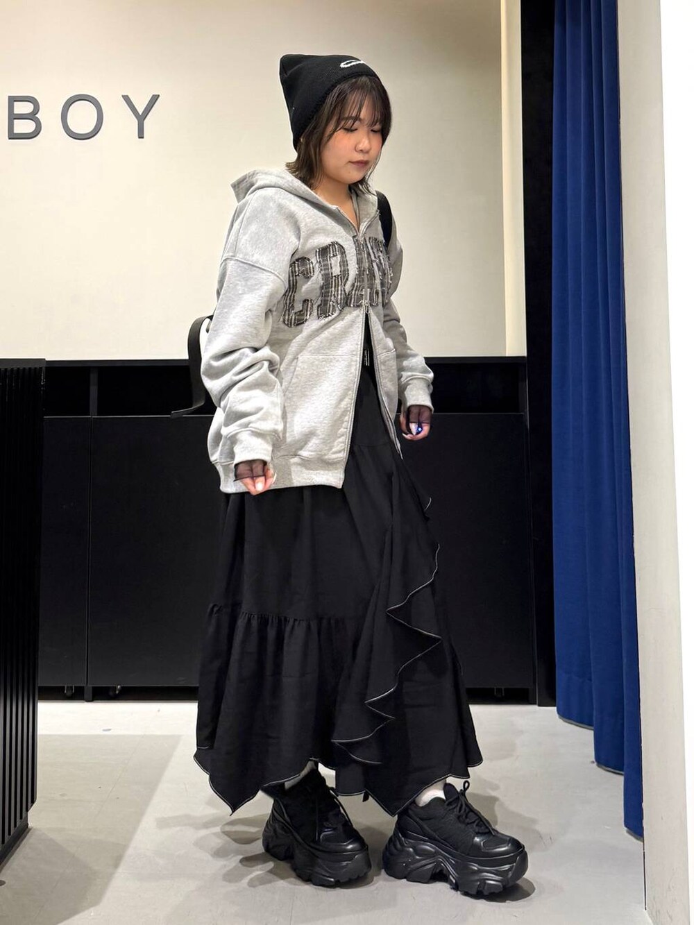 ブラック系のスニーカー、ブラック系のボストンバッグ、ブラック系のスカートを着用したレディースの冬コーディネートの3枚目の写真