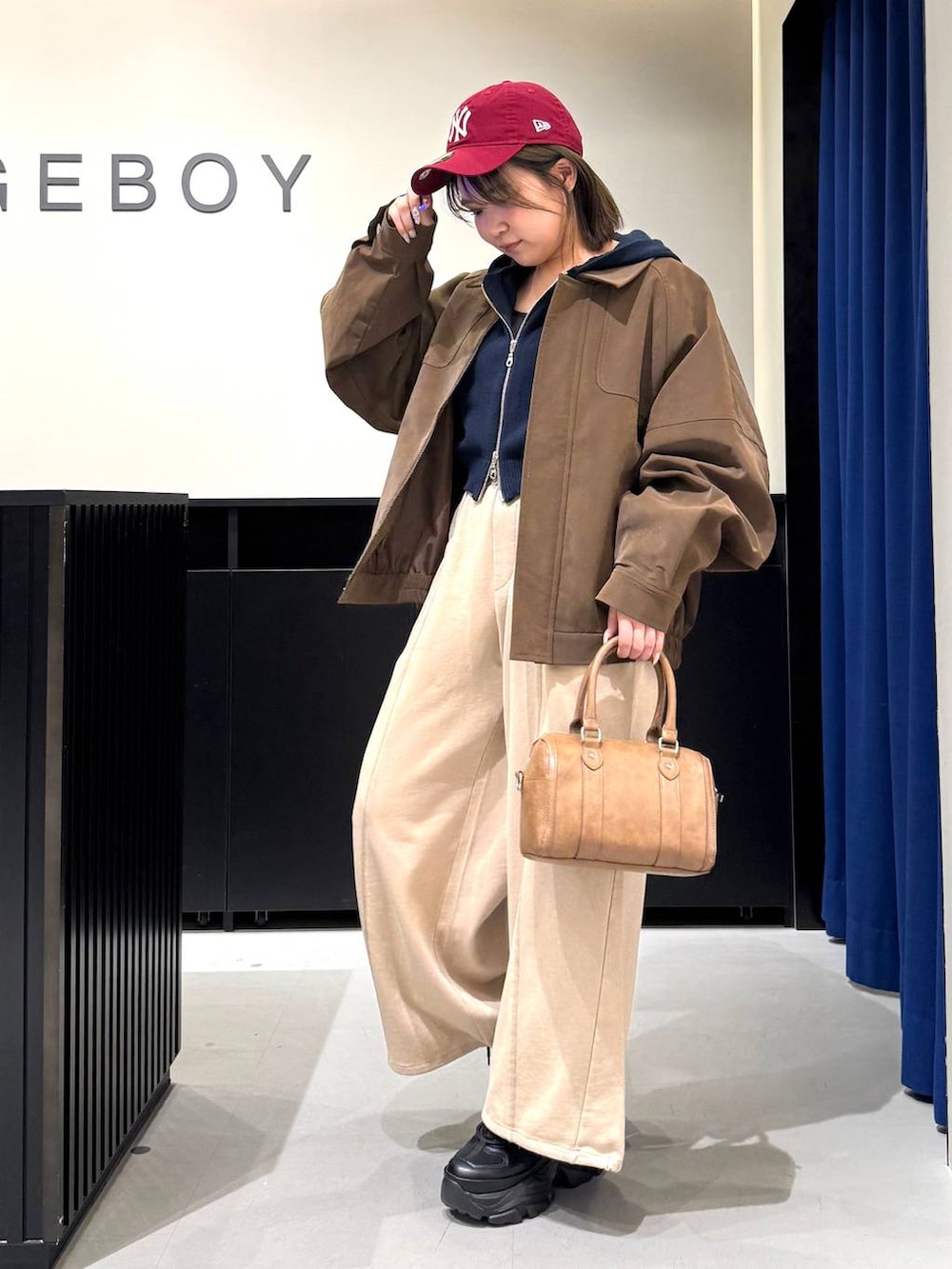 ブラック系のスニーカー、ブラウン系のボストンバッグ、ブルー系のパーカーを着用したレディースの冬コーディネートの7枚目の写真